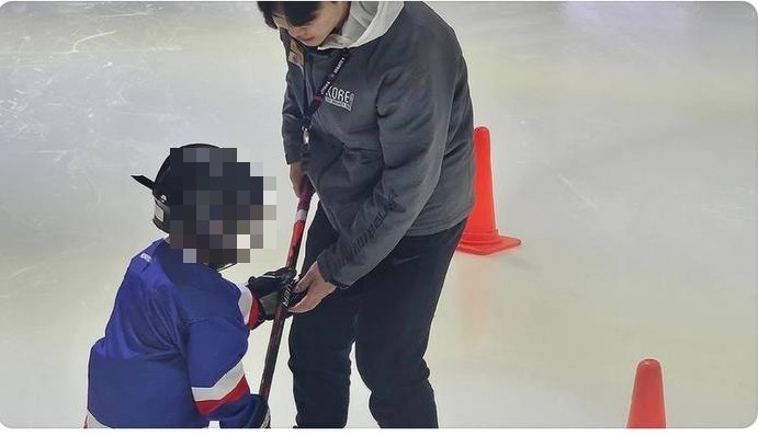 코치가 아이에게 1:1로 스틱을 잡아주는 모습